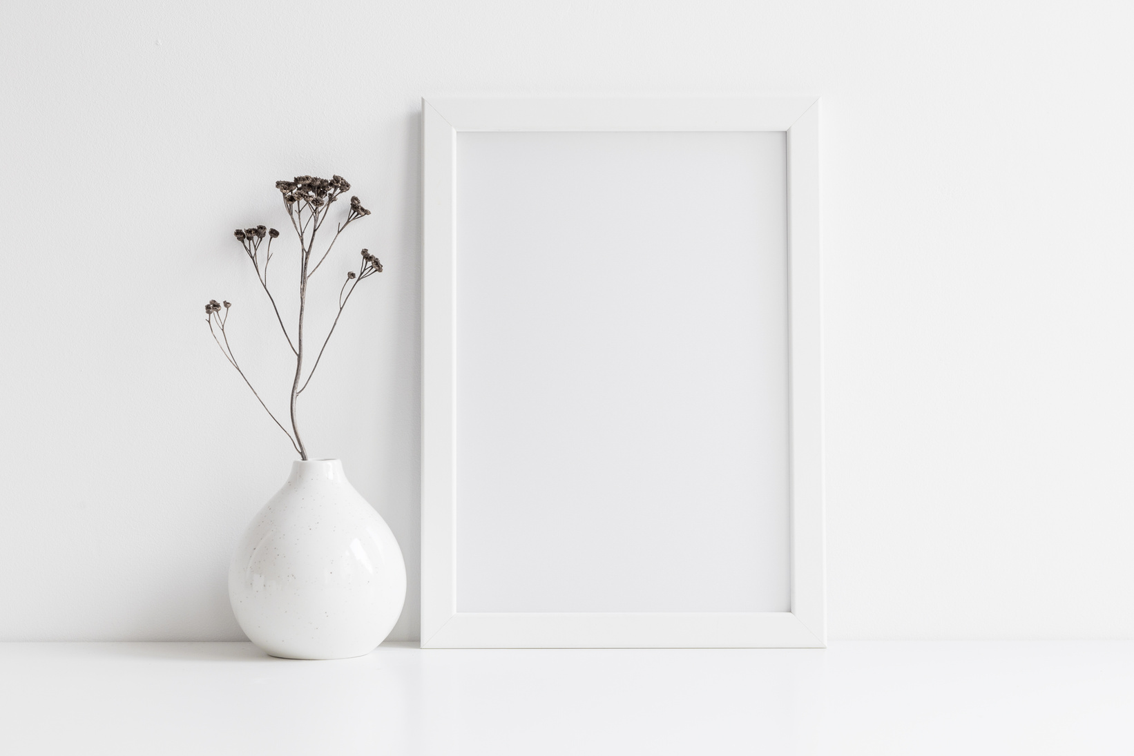 Picture frame mock up and vase with decorative plant.